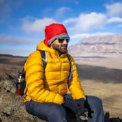 A man relaxing on Mount Kilimanjaro's slopes, dressed in warm outdoor clothing.
