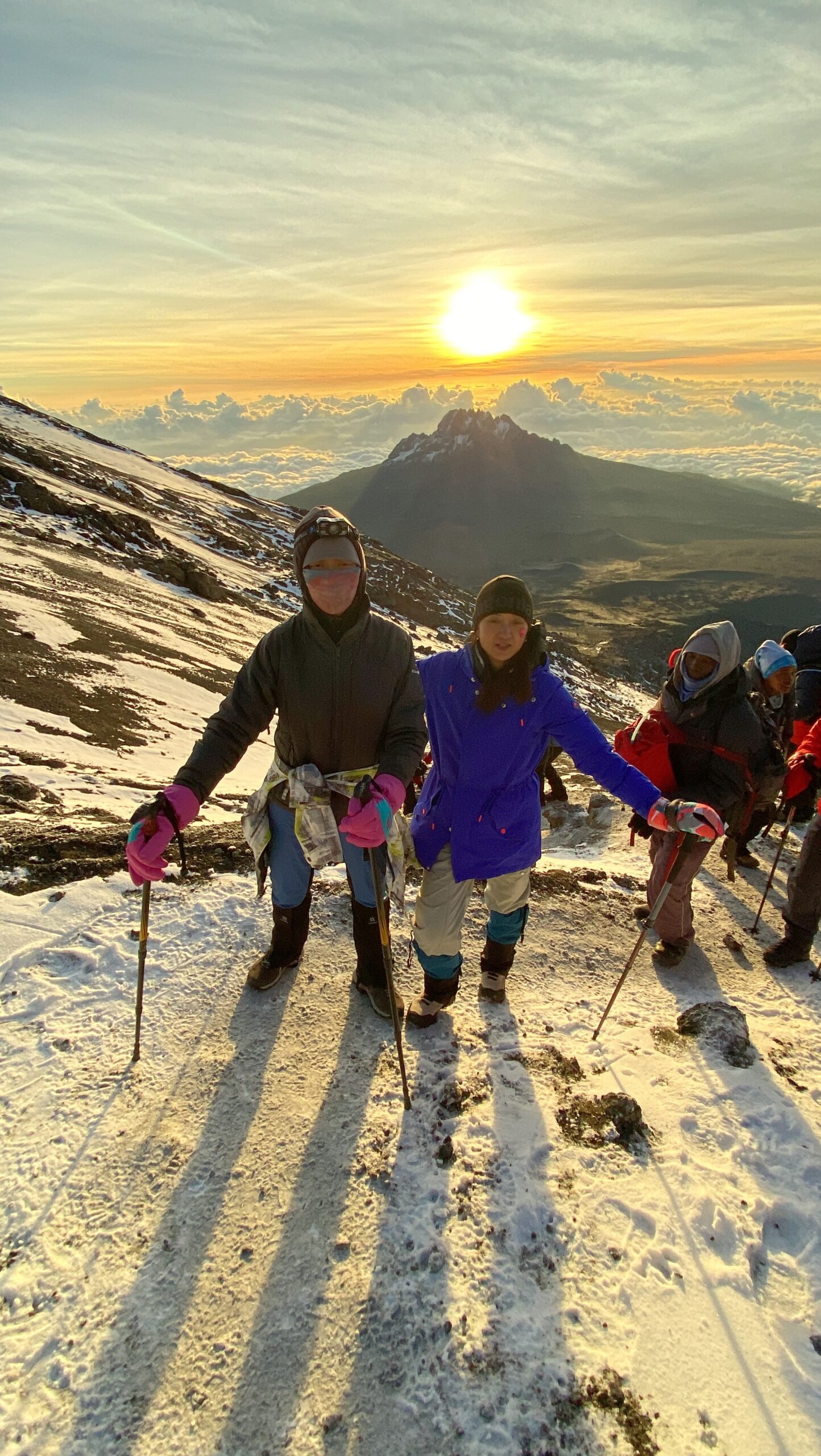 Senior Kilimanjaro guides assisting climbers using trekking poles during the descent from Uhuru Peak on Mount Kilimanjaro, Tanzania. Kilimanjaro hiking Poles