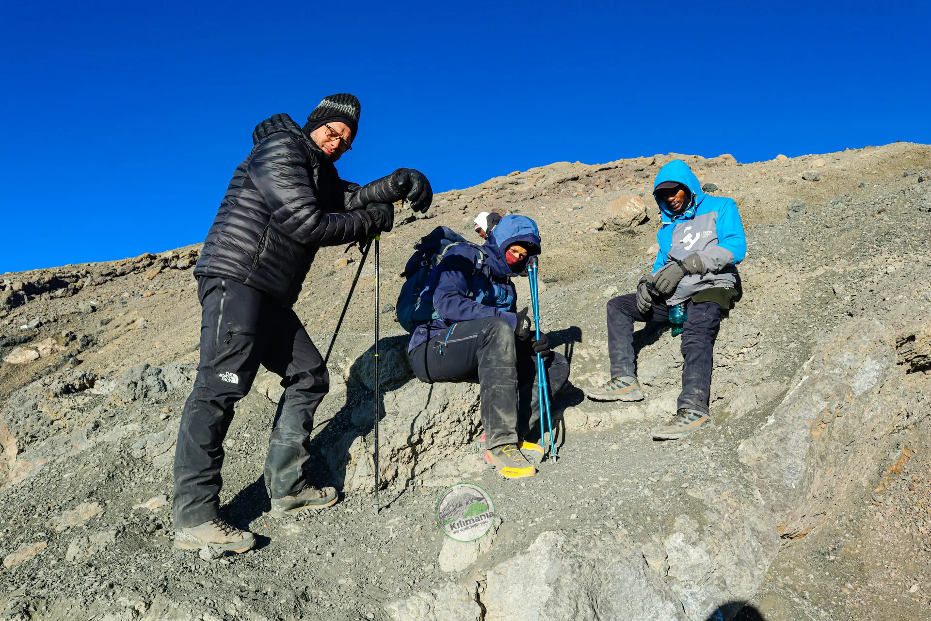 A climber rests during the summit approach on Kilimanjaro; altitude reduces oxygen levels affecting breathing, heart rate, and energy. Photo by Sabinus Msimba, Kilimania Adventure.