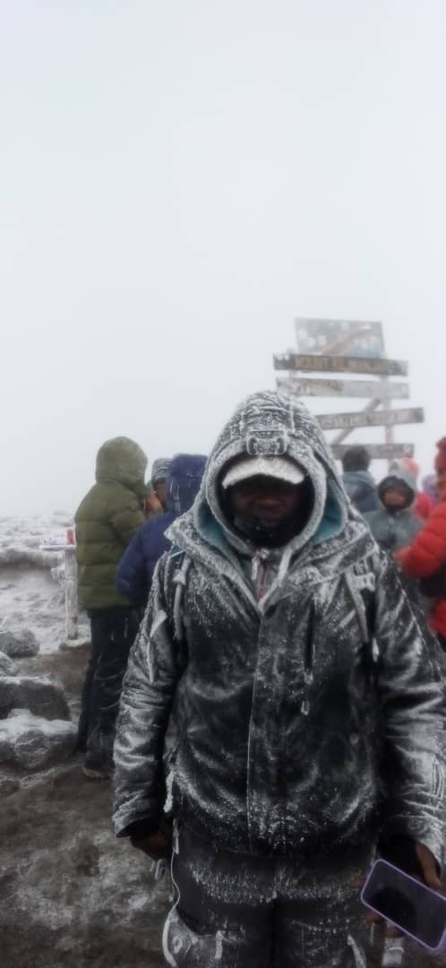 Sabinus Msimba at the Uhuru Peak summit sign, Mount Kilimanjaro