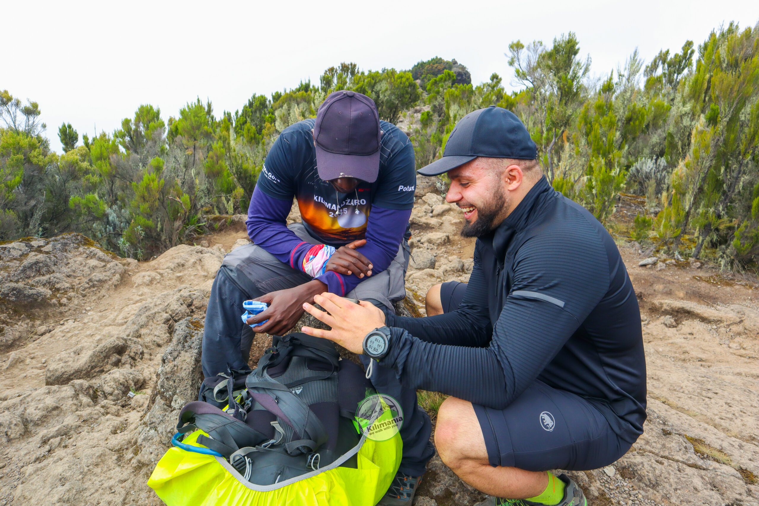 Senior guide Sabinus Msimba checking on a client during a rest break on the Shira Plateau, Mount Kilimanjaro