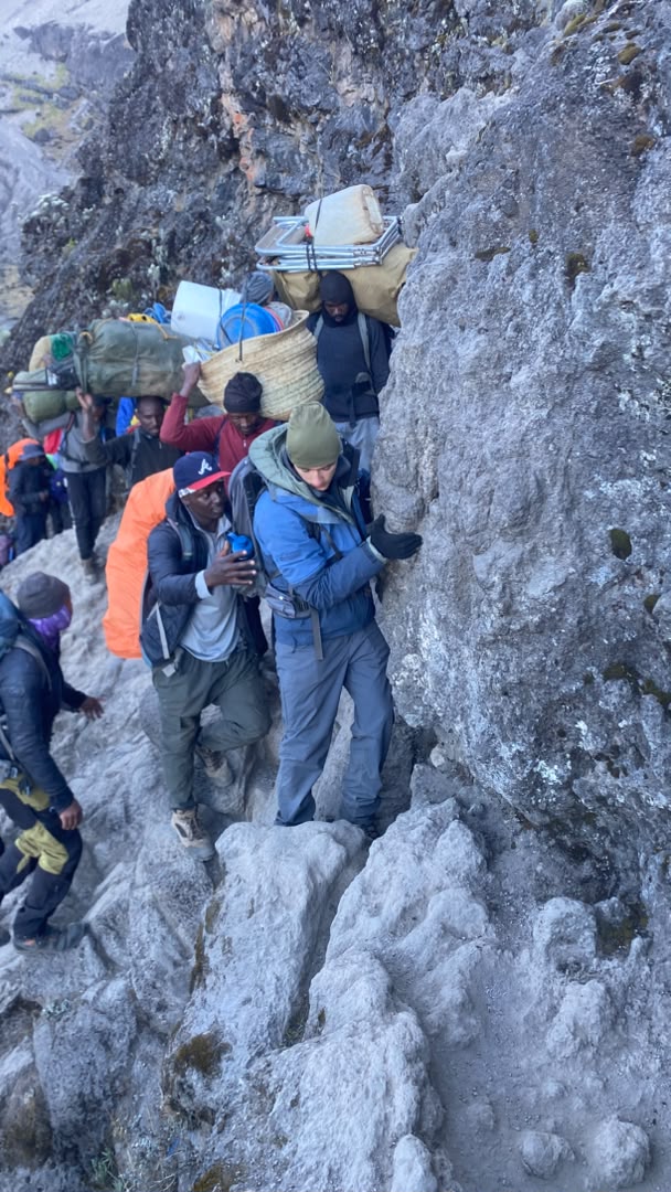 A mother and her two children climbing the Barranco Wall on the Lemosho Route with Kilimania Adventure guide support — family Kilimanjaro climbing Barranco Wall