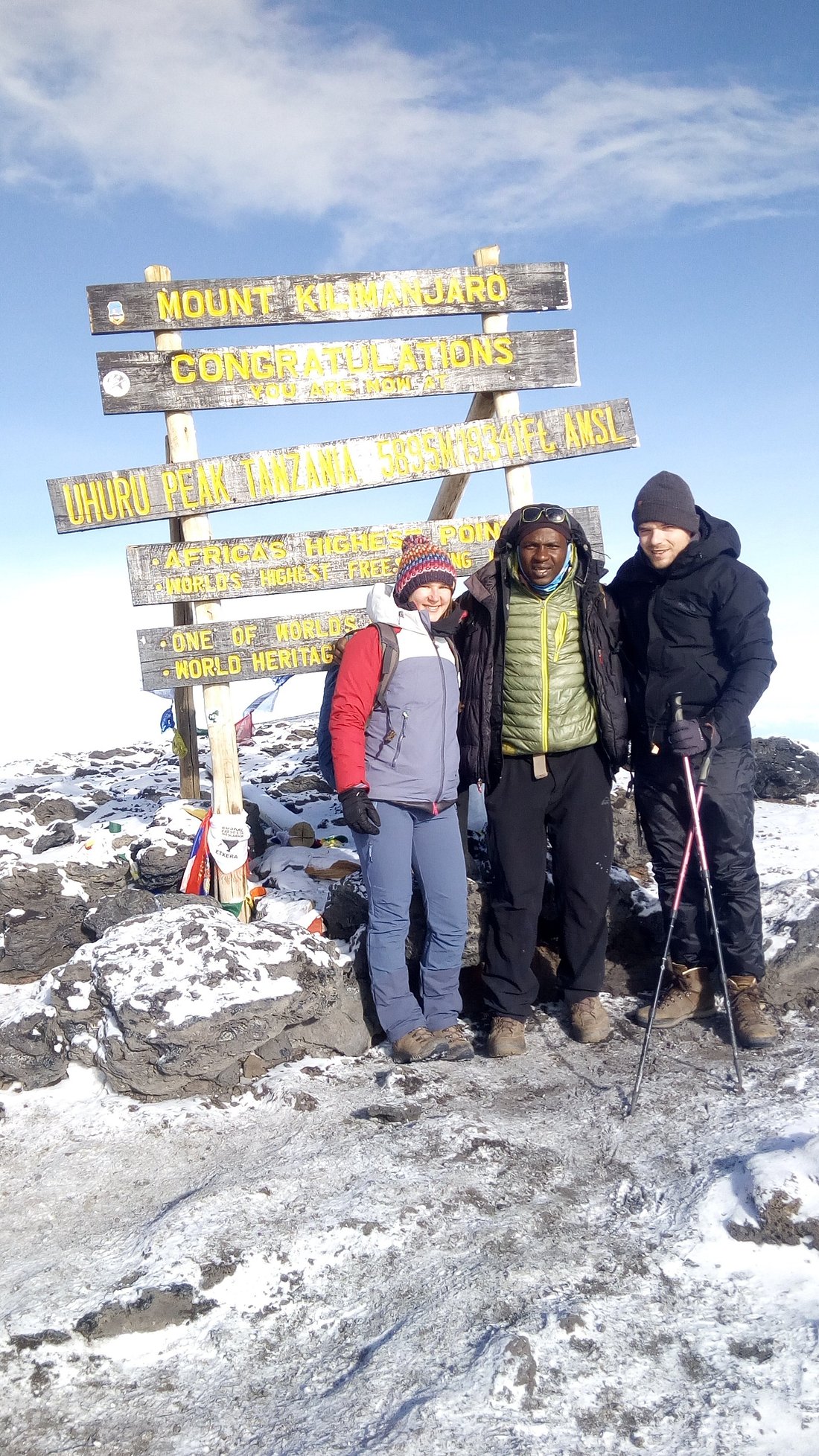 Sabinus Msimba with climbers at Uhuru Peak summit sign