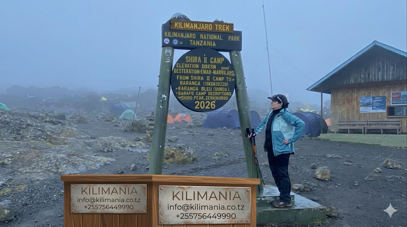 A climber pauses beside the Shira Camp sign on Mount Kilimanjaro's Lemosho Route during the Kilimania Adventure trek to Uhuru Peak