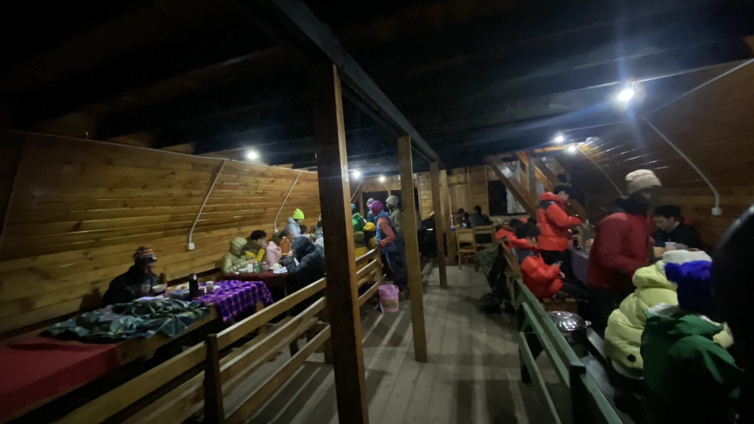 Climbers eating dinner in the wooden dining room of Mandara Hut on Kilimanjaro's Marangu Route at night