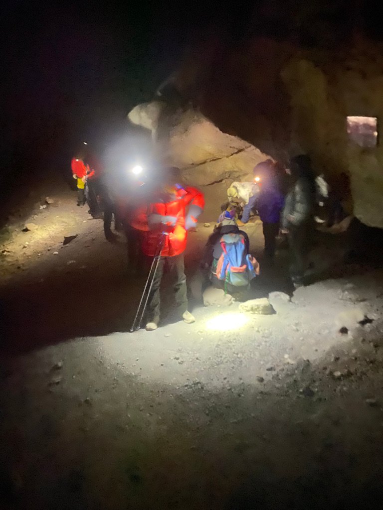 Kilimanjaro summit night climbers sheltering briefly at a rock feature with headlamps glowing during the ascent above Barafu Camp