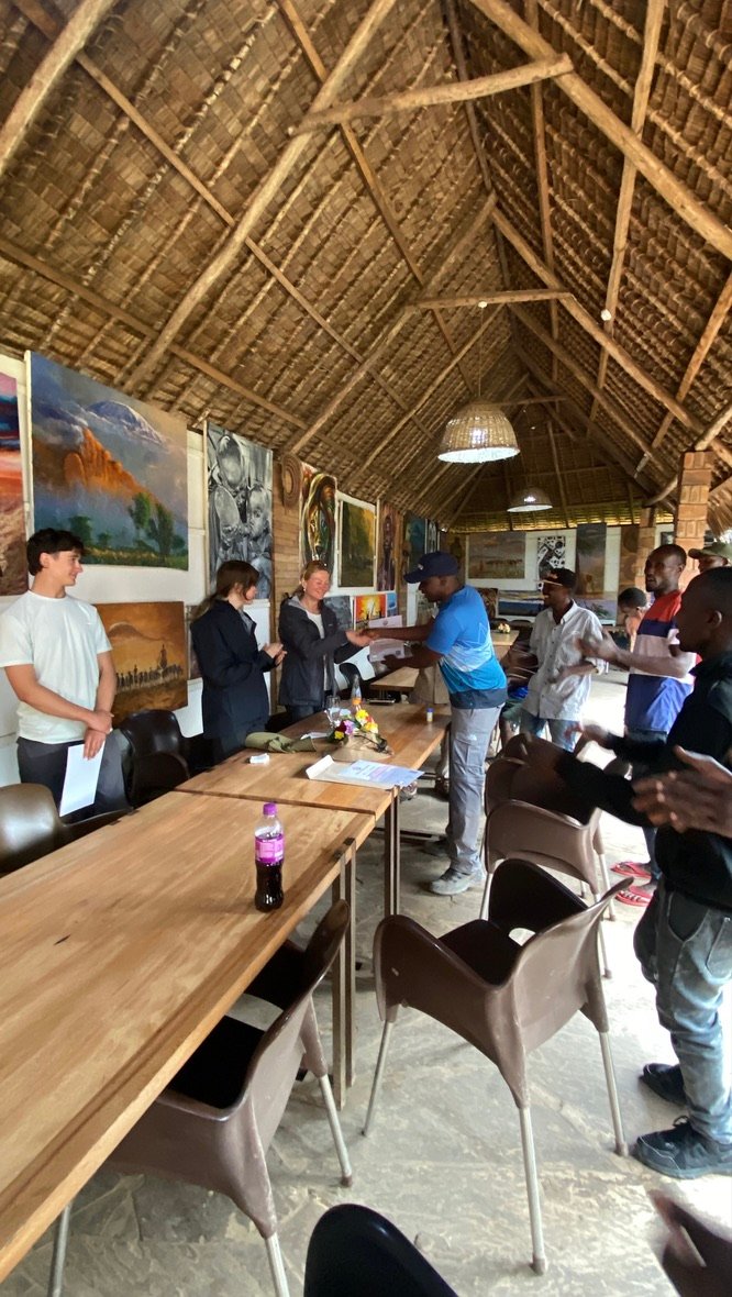 Kilimanjaro climbers receiving summit certificates with guide Sabinus Msimba in Moshi, Tanzania
