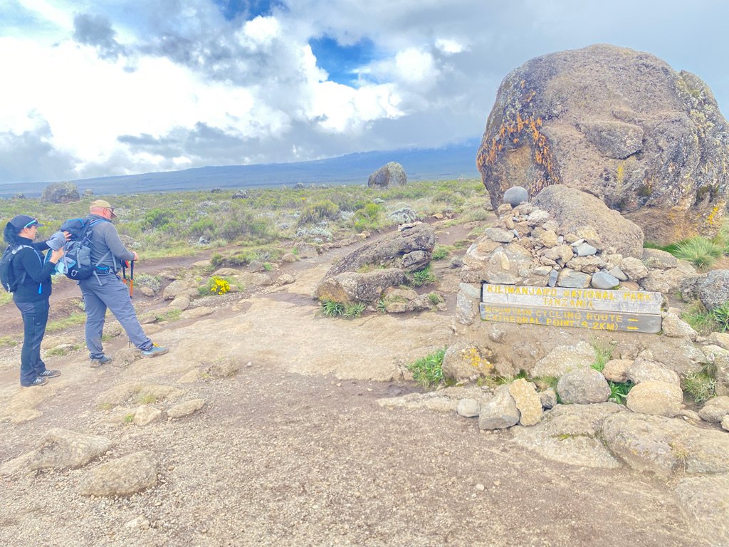Two hikers standing near the Cathedral Point trail marker on the open Shira Plateau