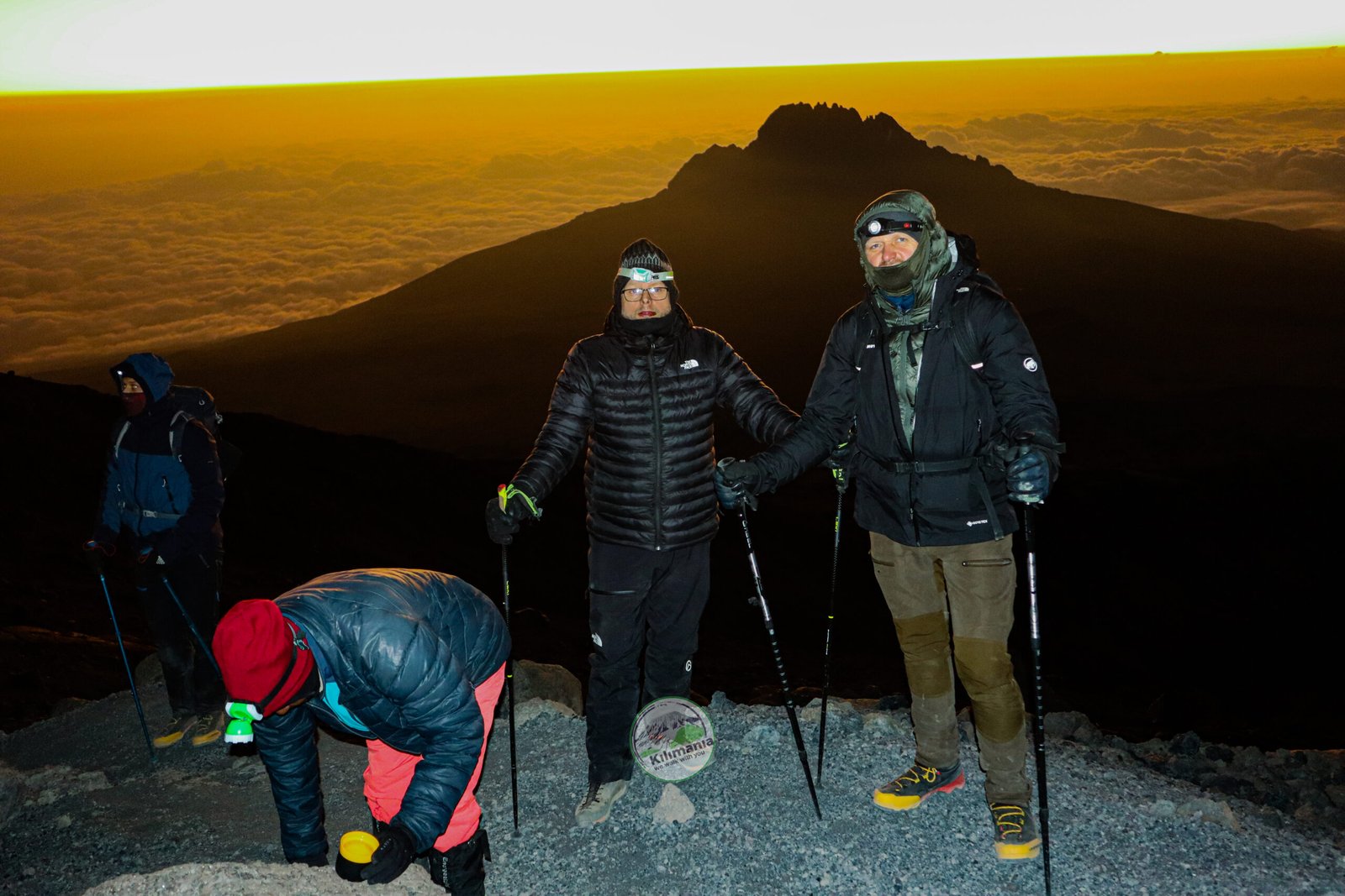 Kilimania climbing group at dawn near Uhuru Peak summit sign, Kilimanjaro