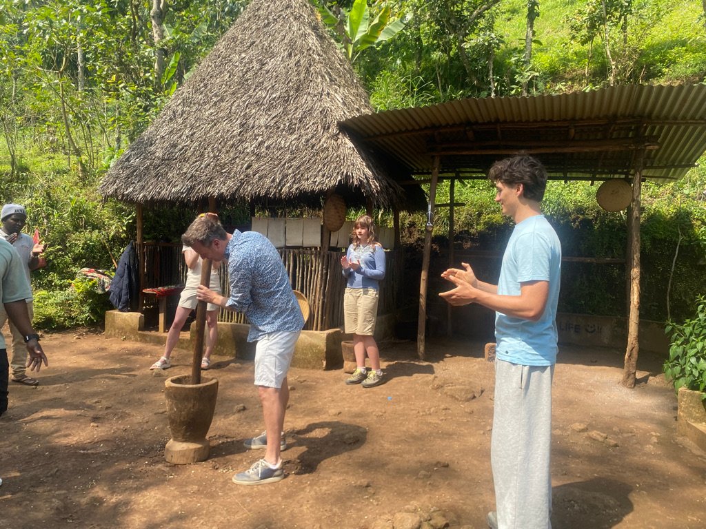 Grinding roasted coffee beans with a traditional wooden mortar and pestle at Materuni Village