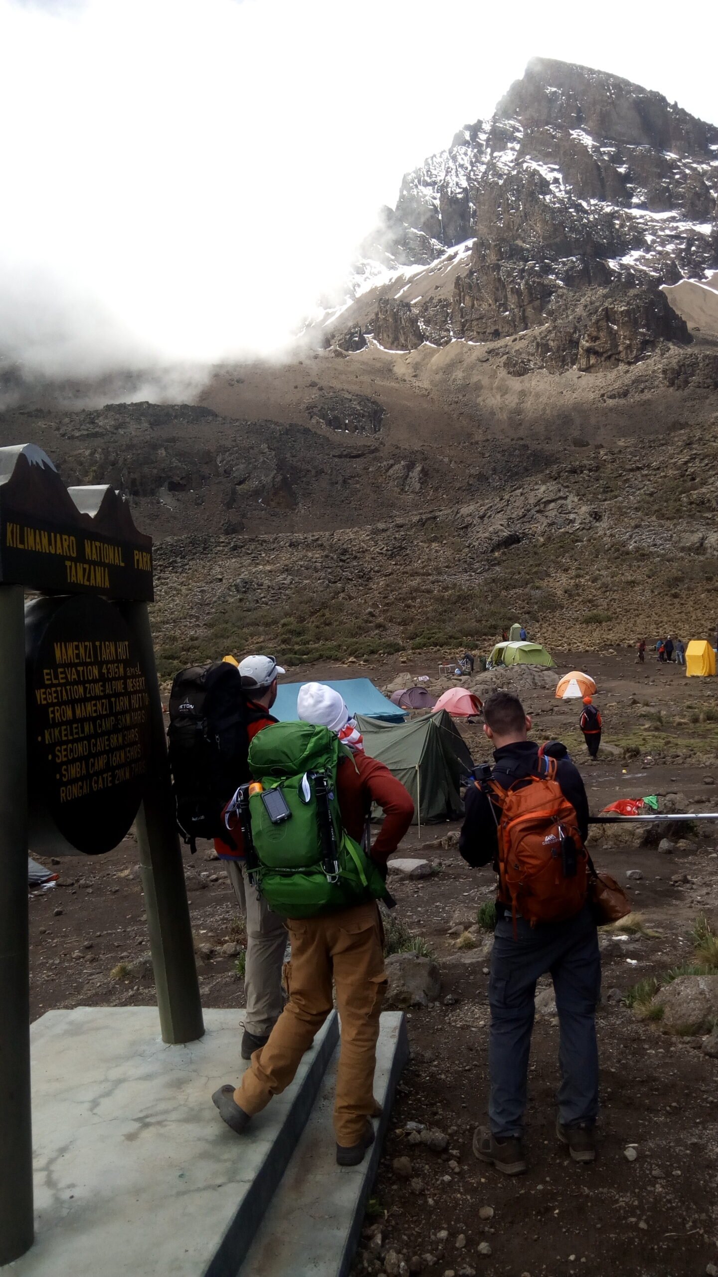 Climbers beside a camp sign on Kilimanjaro's northern Rongai side
