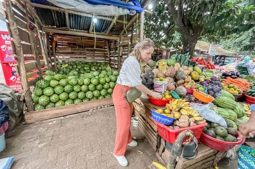 Traveller buying fruit from a trader at a stall in Moshi's local market